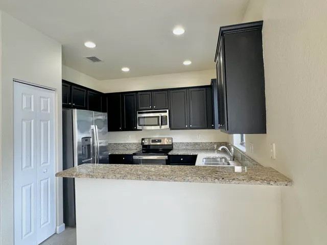 a large kitchen with stainless steel appliances granite countertop a sink refrigerator and microwave