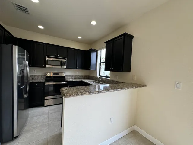 a kitchen with stainless steel appliances granite countertop a refrigerator a stove a sink and a microwave