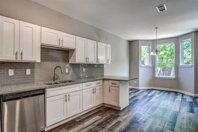 a kitchen with stainless steel appliances granite countertop a sink a stove a white cabinets and wooden floor