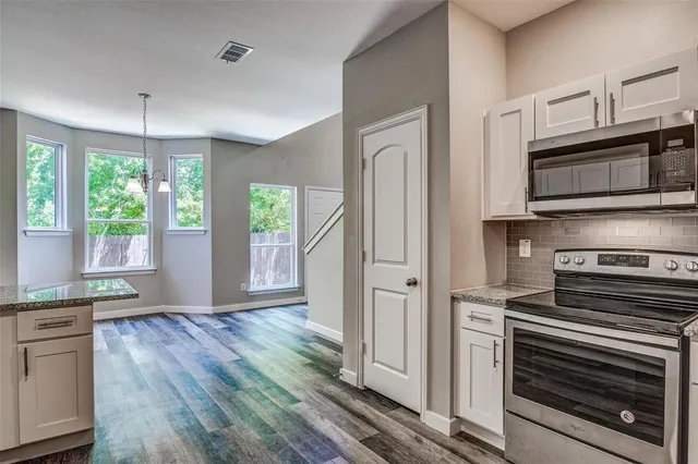 a kitchen with granite countertop a stove and a microwave