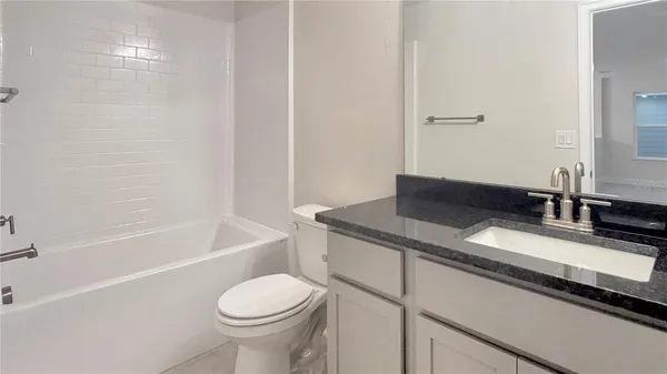 a bathroom with a granite countertop toilet sink and mirror