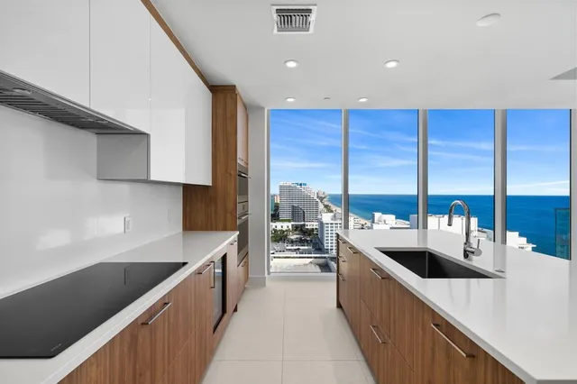 a large kitchen with stainless steel appliances a large counter top a stove a sink a refrigerator and a cabinets