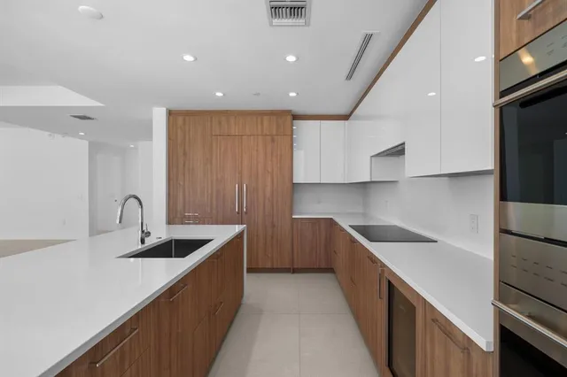 a kitchen with kitchen island granite countertop a sink and refrigerator