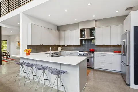 a kitchen with a sink a stove a refrigerator and white cabinets with wooden floor