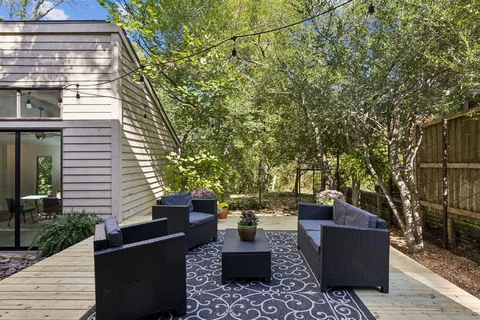 a view of a patio with couches and table and chairs with wooden floor and fence