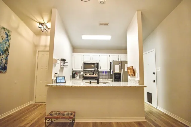 a room with kitchen island stainless steel appliances a sink and a counter top space