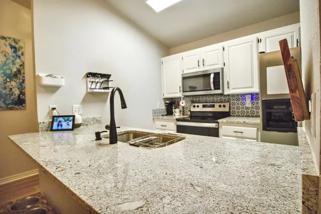 a kitchen with stainless steel appliances granite countertop a sink and a microwave