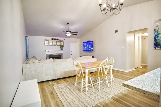 a dining room with wooden floor a chandelier a wooden table and chairs