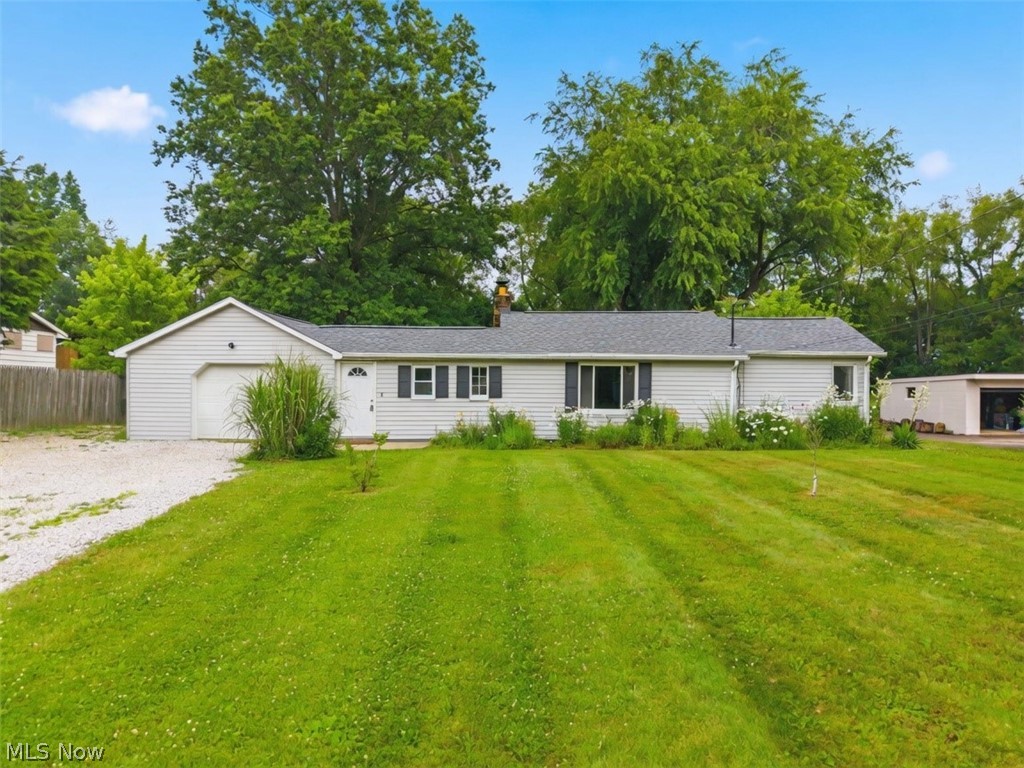 Ranch-style exterior with light-colored siding, a single-car garage, and a gravel driveway