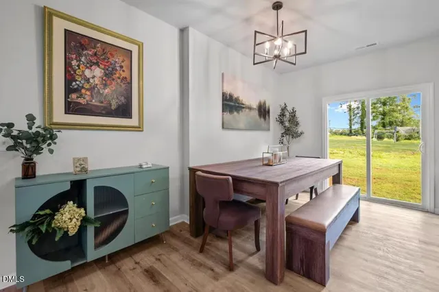 a dining room with wooden floor a chandelier a wooden table and chairs