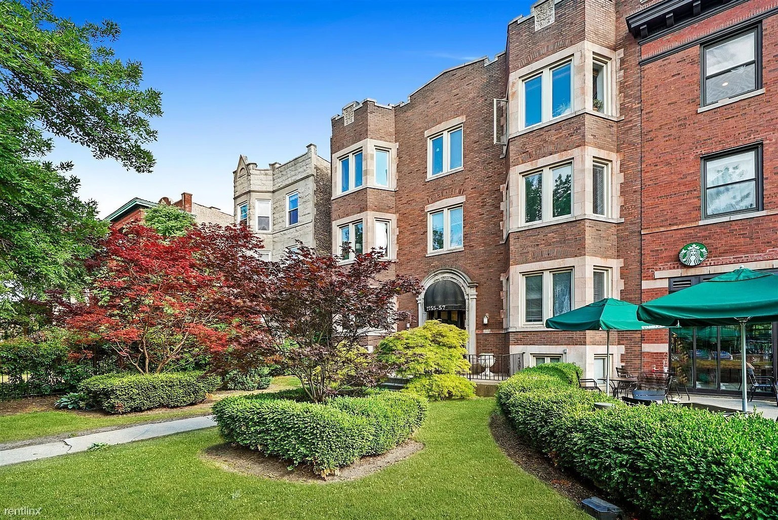 a front view of a building with a garden and plants