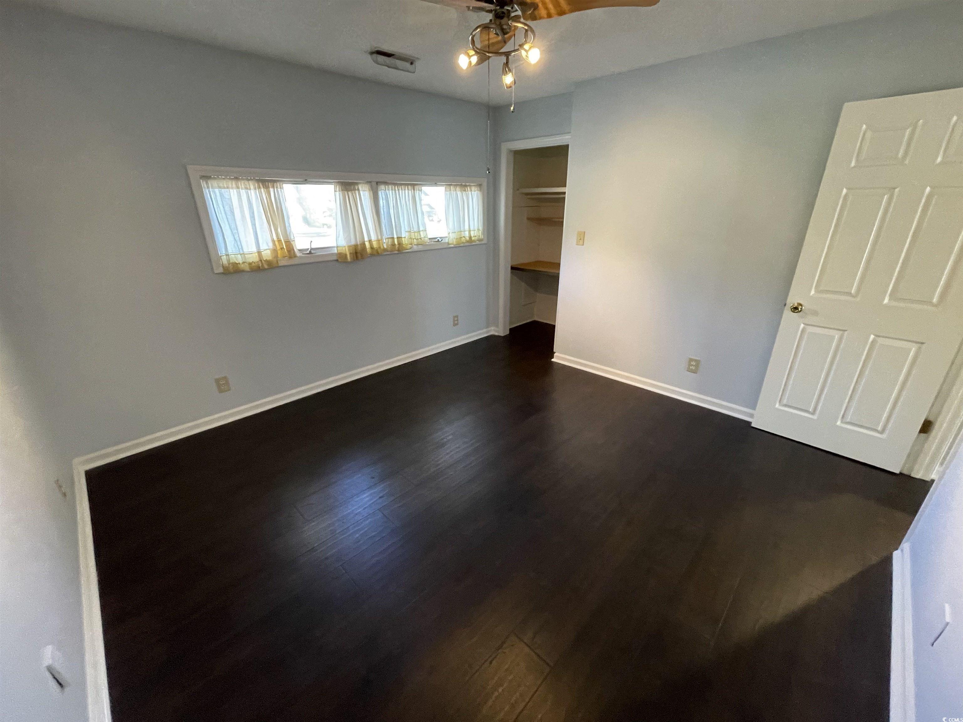 1851 Fairway Ridge Drive, Unit 7E Surfside Beach, SC 29575 - Photo 14 of 29 Unfurnished bedroom featuring dark wood-style flooring, a closet, and a ceiling fan
