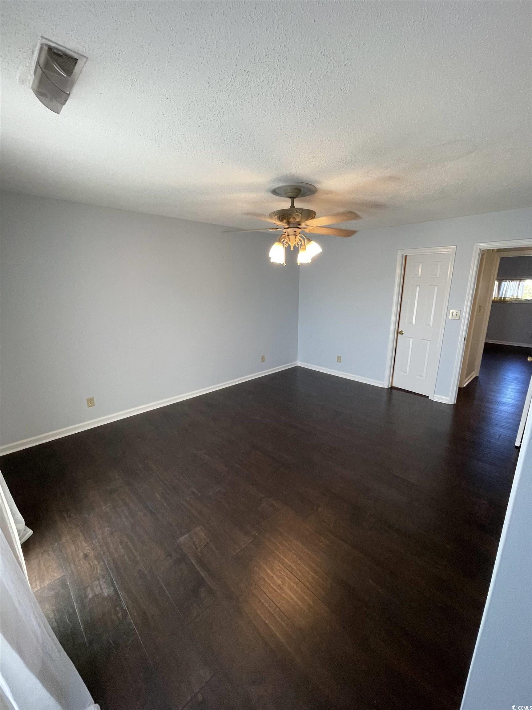 1851 Fairway Ridge Drive, Unit 7E Surfside Beach, SC 29575 - Photo 15 of 29 Unfurnished room featuring dark wood finished floors, a textured ceiling, and ceiling fan