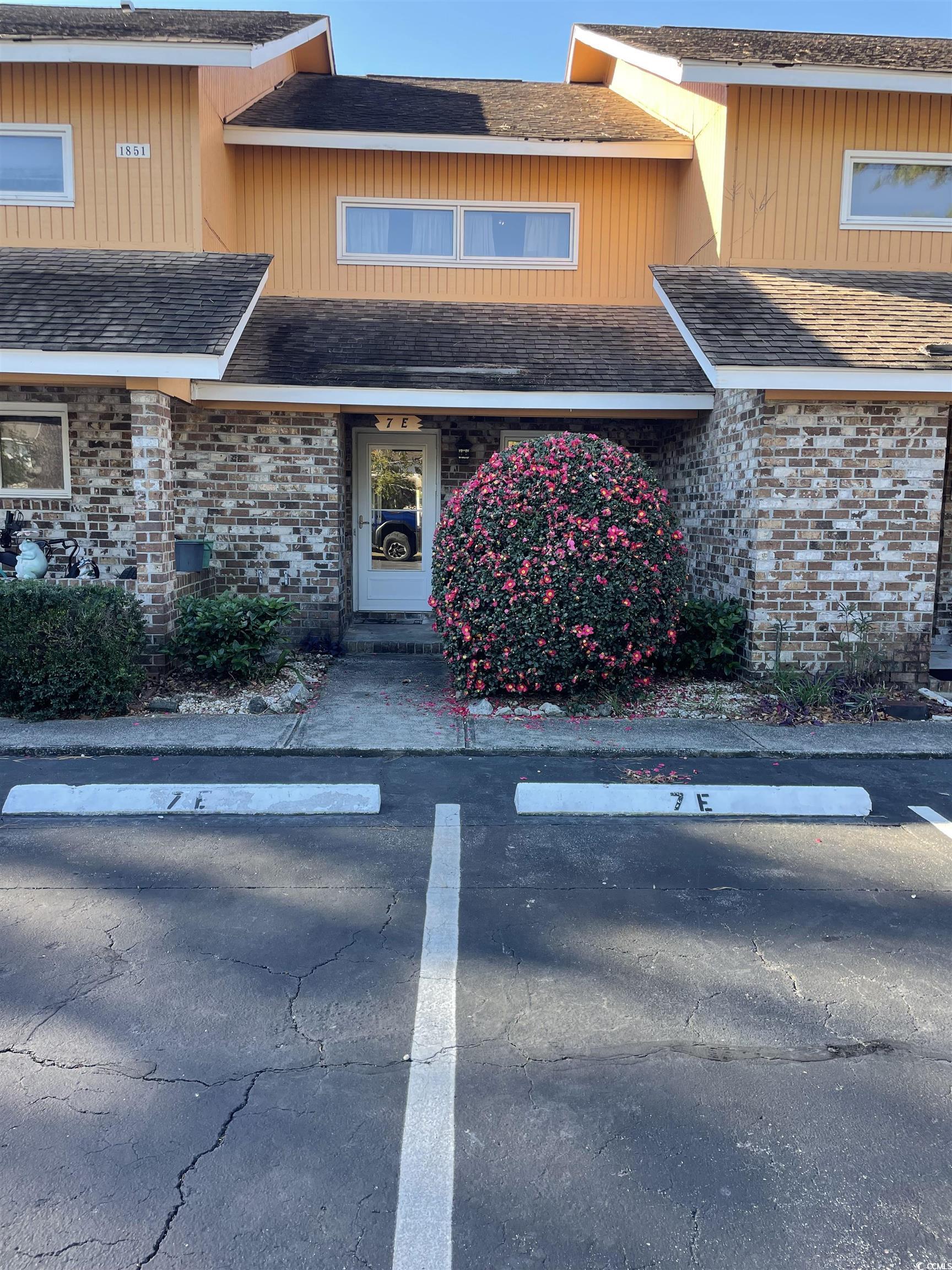 1851 Fairway Ridge Drive, Unit 7E Surfside Beach, SC 29575 - Photo 22 of 29 View of front facade with a shingled roof, brick siding, and uncovered parking