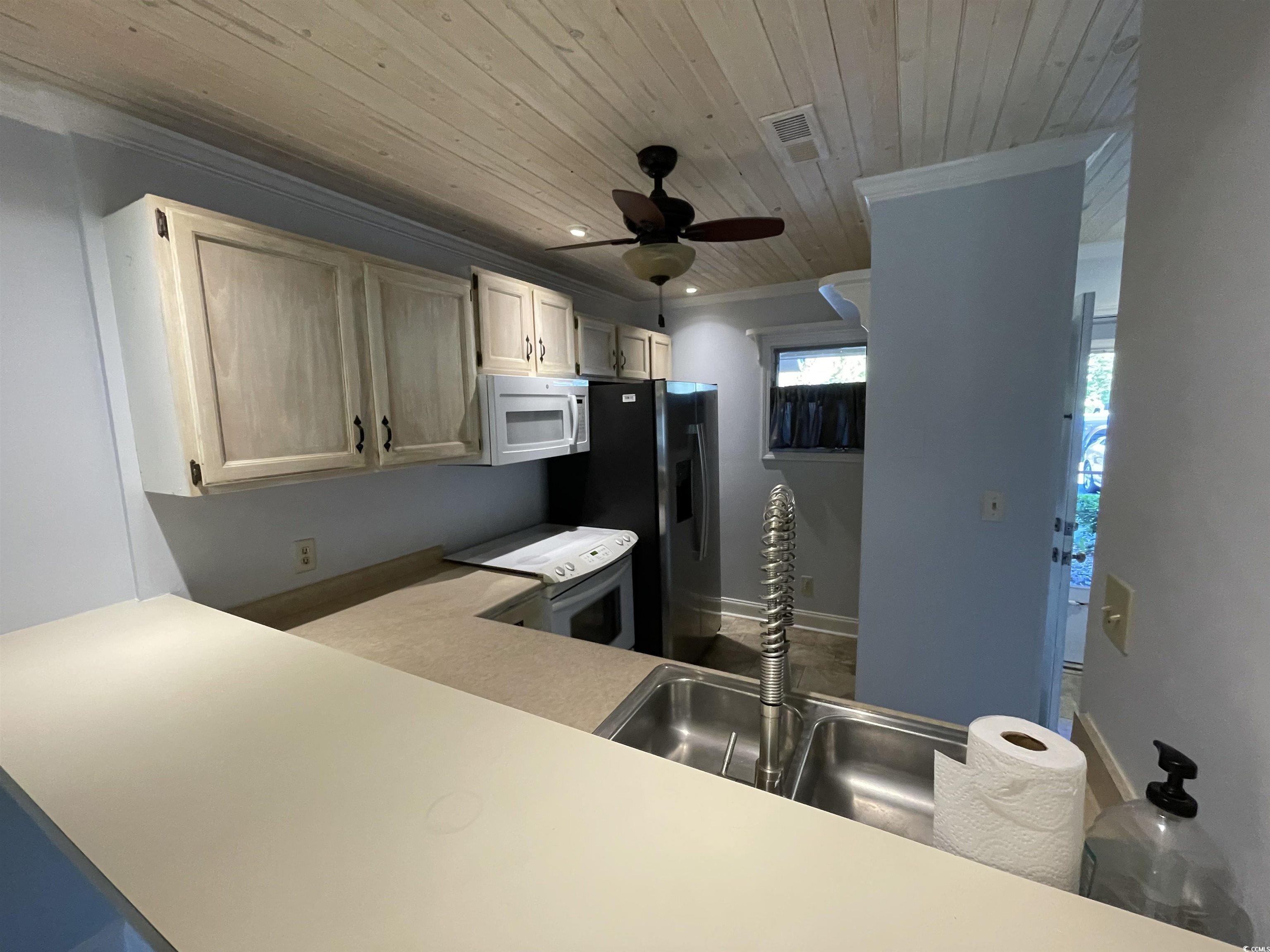 1851 Fairway Ridge Drive, Unit 7E Surfside Beach, SC 29575 - Photo 4 of 29 Kitchen with white appliances, wood ceiling, light countertops, ceiling fan, and ornamental molding