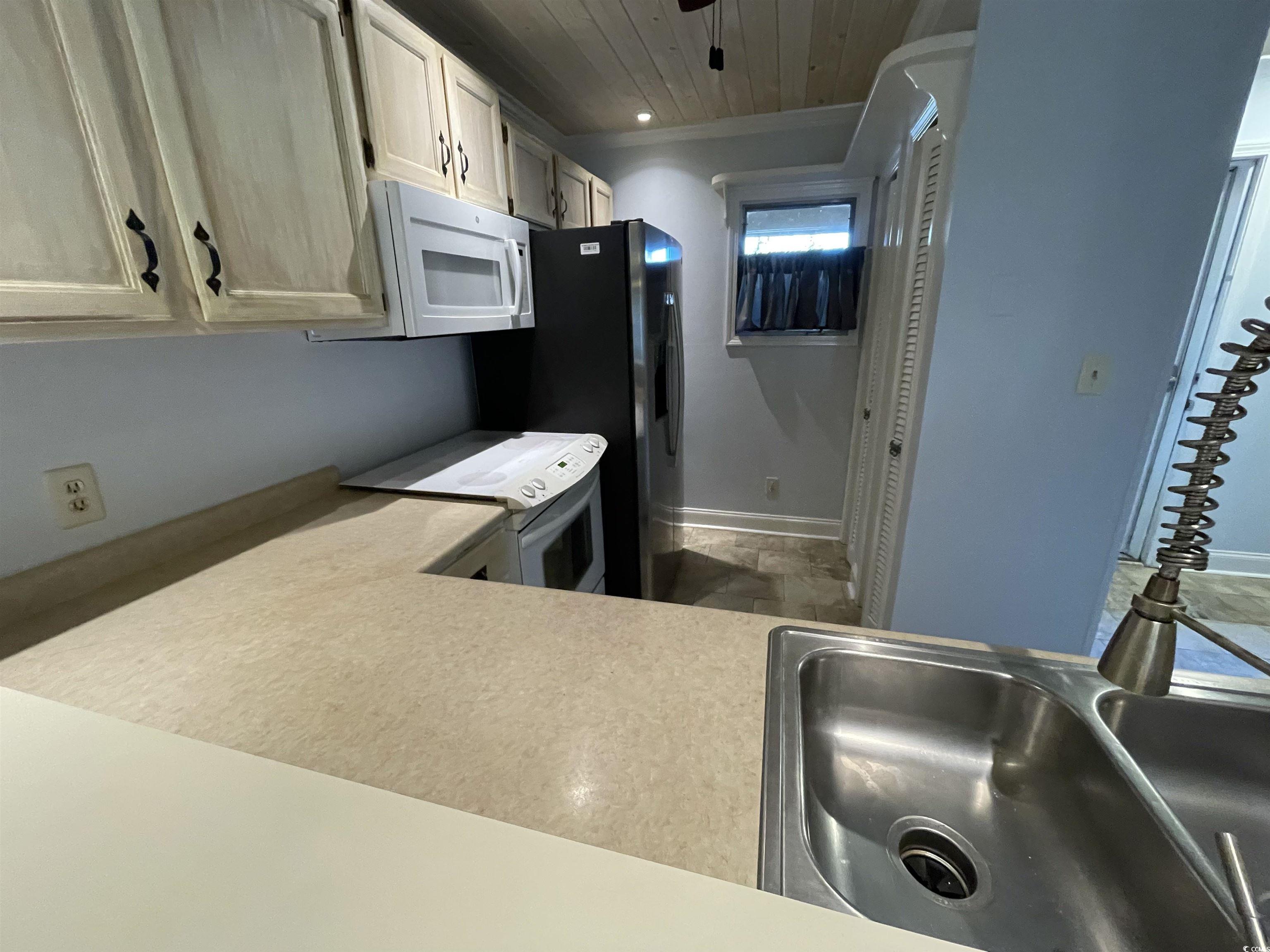 1851 Fairway Ridge Drive, Unit 7E Surfside Beach, SC 29575 - Photo 5 of 29 Kitchen featuring white appliances, light countertops, wood ceiling, and ornamental molding