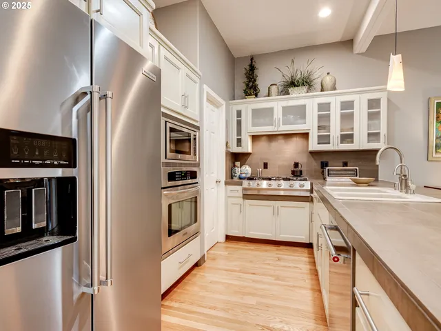 a kitchen with stainless steel appliances a dining table chairs stove and refrigerator