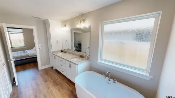 a bathroom with a granite countertop sink mirror and a bathtub