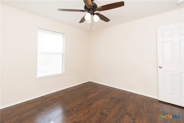 an empty room with a window and a ceiling fan