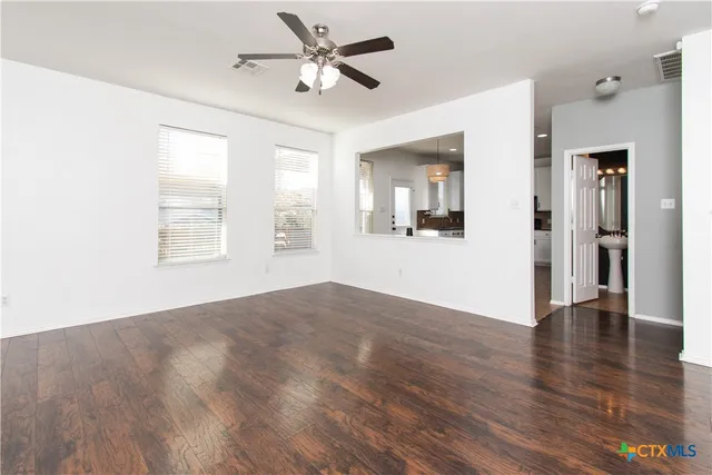 a view of an empty room with window and wooden floor