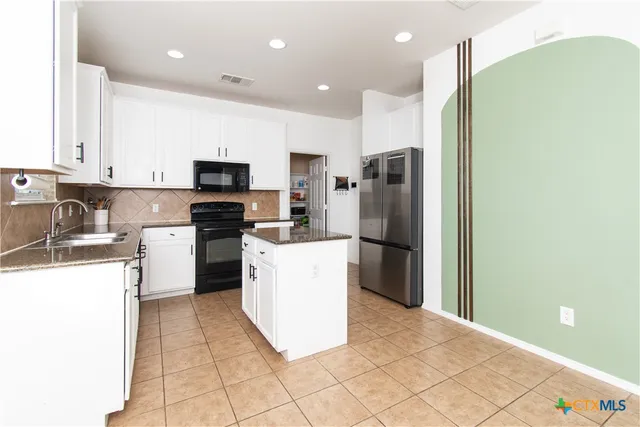 a kitchen with a refrigerator a stove top oven and cabinets