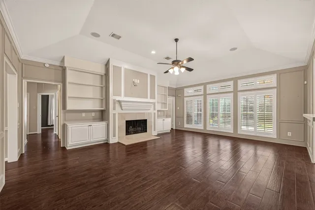 a view of an empty room with wooden floor and a fireplace