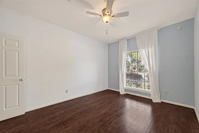 an empty room with wooden floor chandelier fan and windows