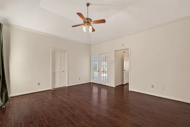 a view of an empty room with wooden floor and a ceiling fan