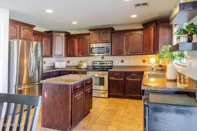 a kitchen with stainless steel appliances granite countertop a stove top oven a sink dishwasher a dining table and chairs with wooden floor