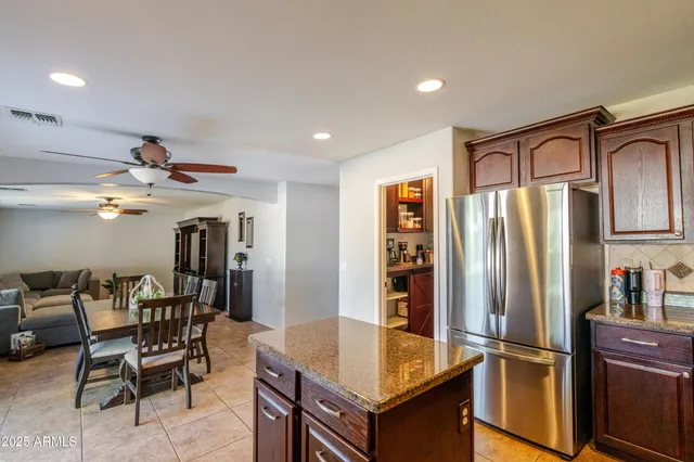 a kitchen with stainless steel appliances granite countertop a refrigerator a sink and a stove with wooden floor