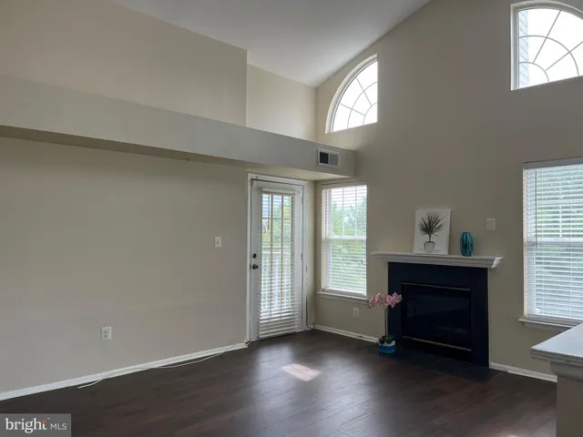an empty room with wooden floor a ceiling fan and windows