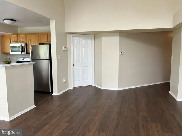 a view of a kitchen with wooden floor electronic appliances and a refrigerator