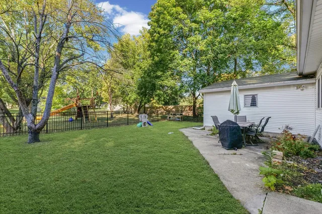 a view of a backyard with table and chairs potted plants and large tree