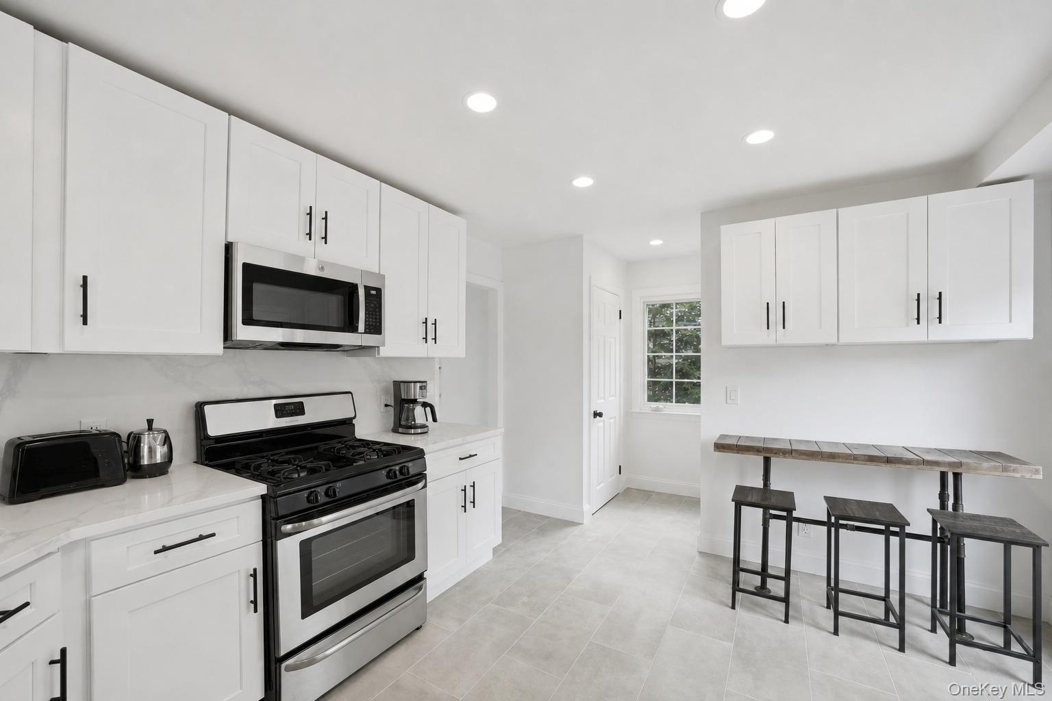 144 Bell Road Scarsdale, NY 10583 - Photo 12 of 49 Kitchen featuring white shaker cabinetry, stainless steel appliances, a tile backsplash, and recessed lighting