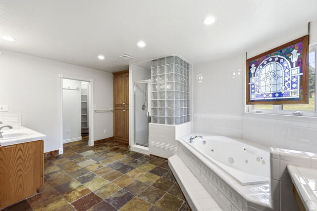 3535 Homestead Road Park City, UT 84098 - Photo 38 of 81 Spacious bathroom featuring a built-in jetted tub, a glass block shower enclosure, and a stained glass window accent