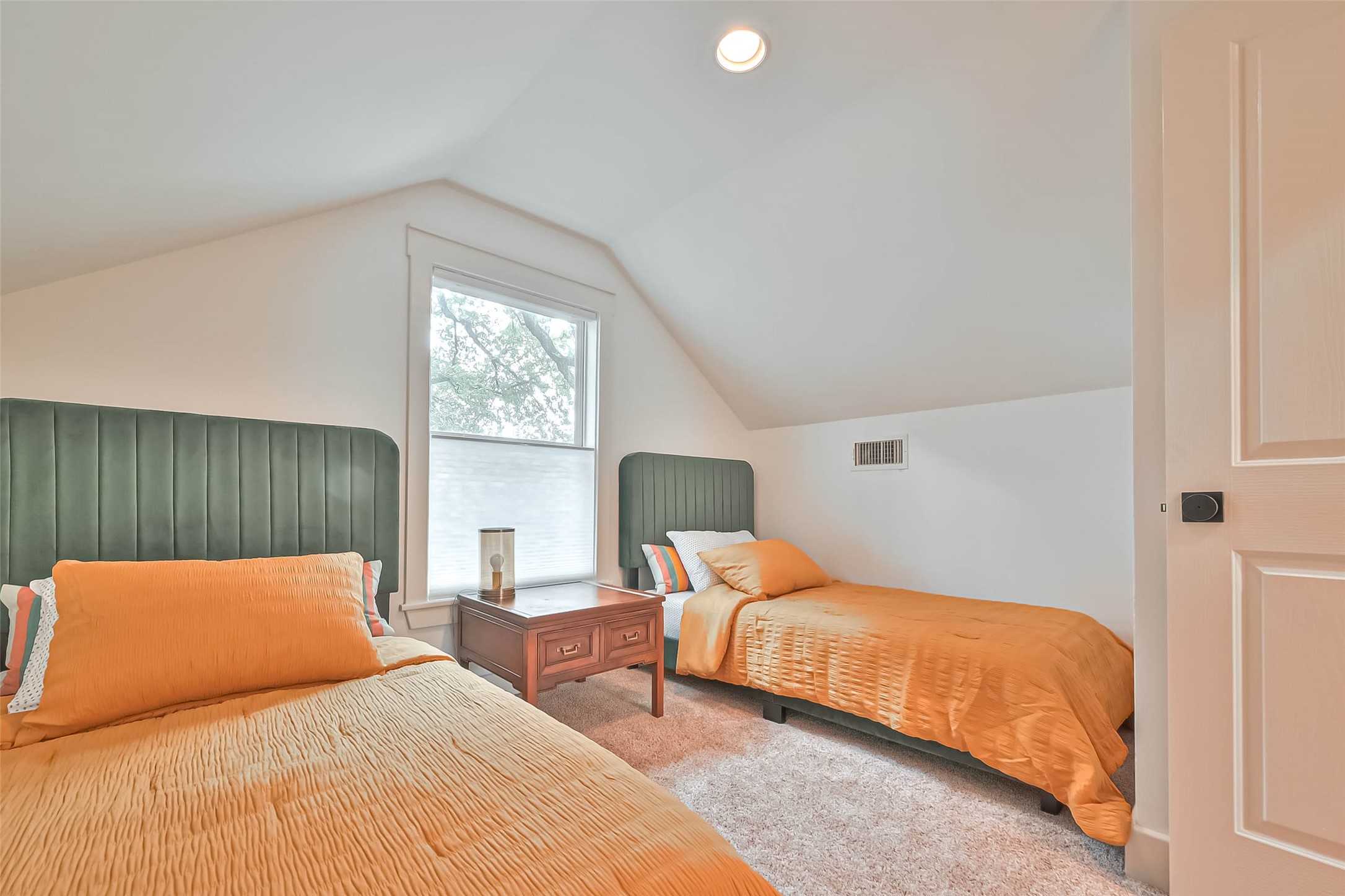 412 Sue Street Houston, TX 77009 - Photo 13 of 19 This cozy upstairs bedroom features two twin beds. A large window allows natural light to fill the room, highlighting the soft carpet flooring. Perfect for a guest.