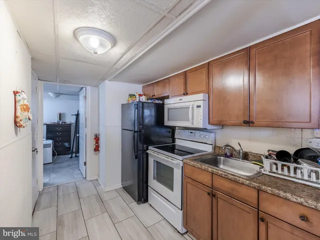 a kitchen with stainless steel appliances granite countertop a refrigerator a sink and white cabinets