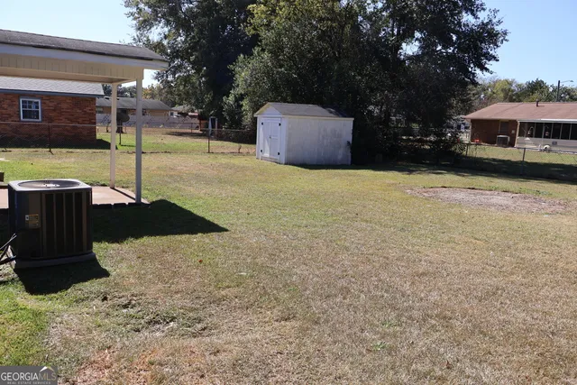 a view of a backyard with table and chairs under an umbrella with large trees