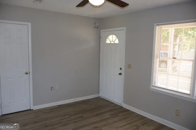 a view of an empty room with wooden floor and a window