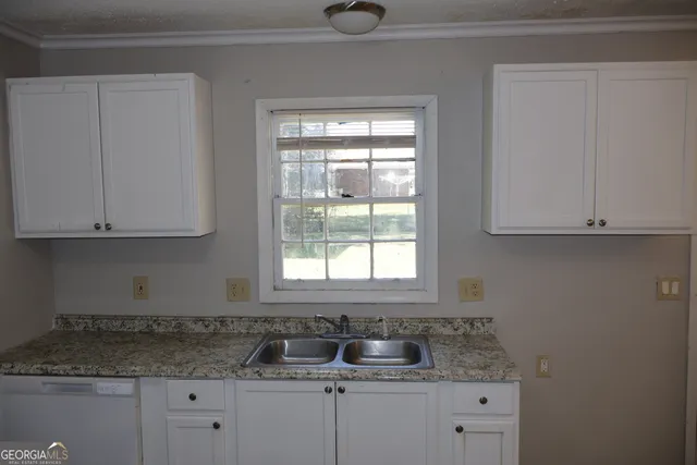 a kitchen with granite countertop white cabinets and a sink