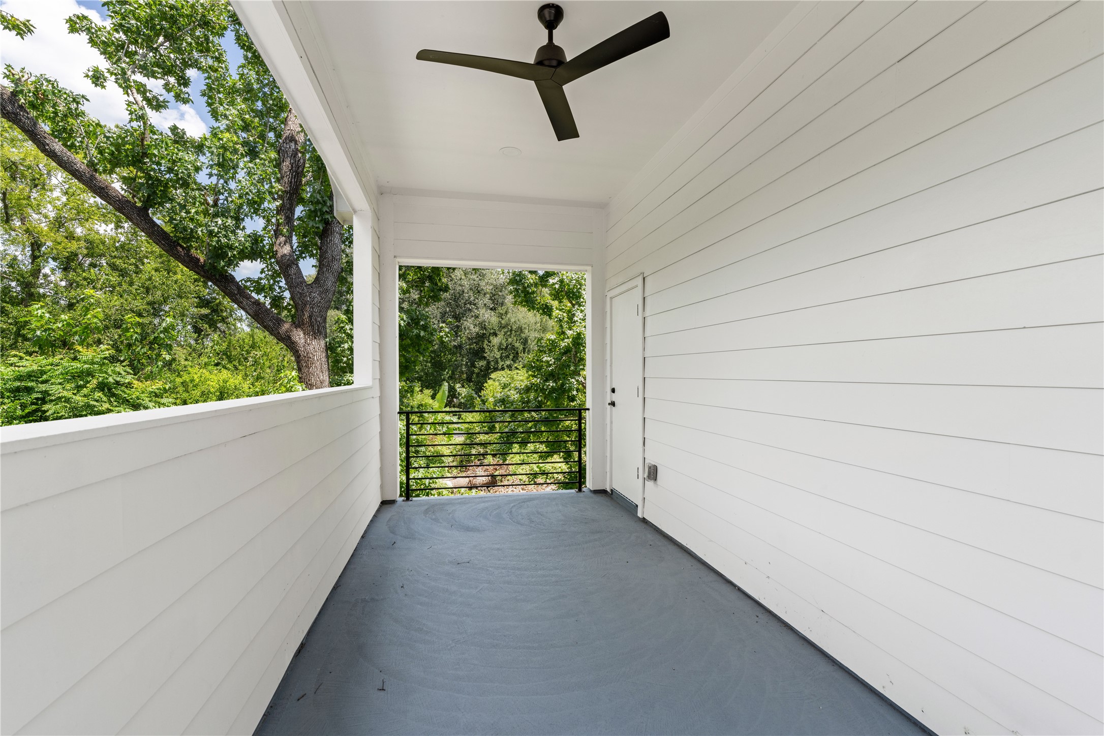 7319 Laura Koppe Road Houston, TX 77028 - Photo 21 of 42 Spacious covered balcony with a ceiling fan, offering serene views of lush greenery.