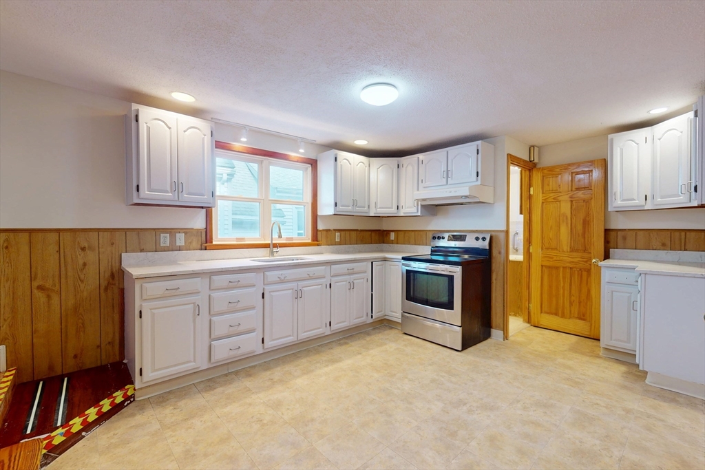 58 Teel Street, Unit 58 Arlington, MA 02474 - Photo 11 of 22 a kitchen with granite countertop white cabinets and stainless steel appliances