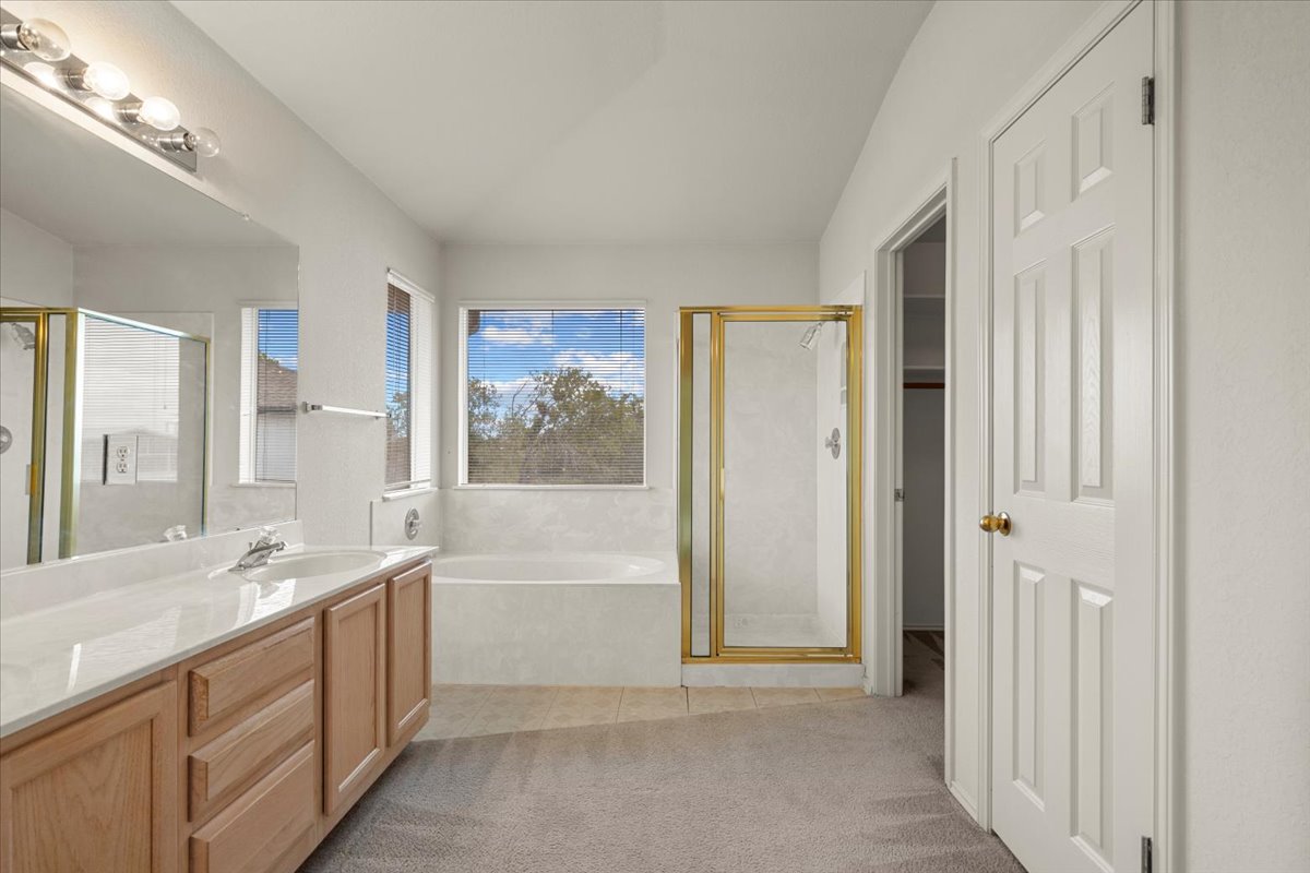 3929 Katzman Drive Austin, TX 78728 - Photo 17 of 29 Bathroom featuring vanity, a stall shower, a garden tub, and light tile patterned floors