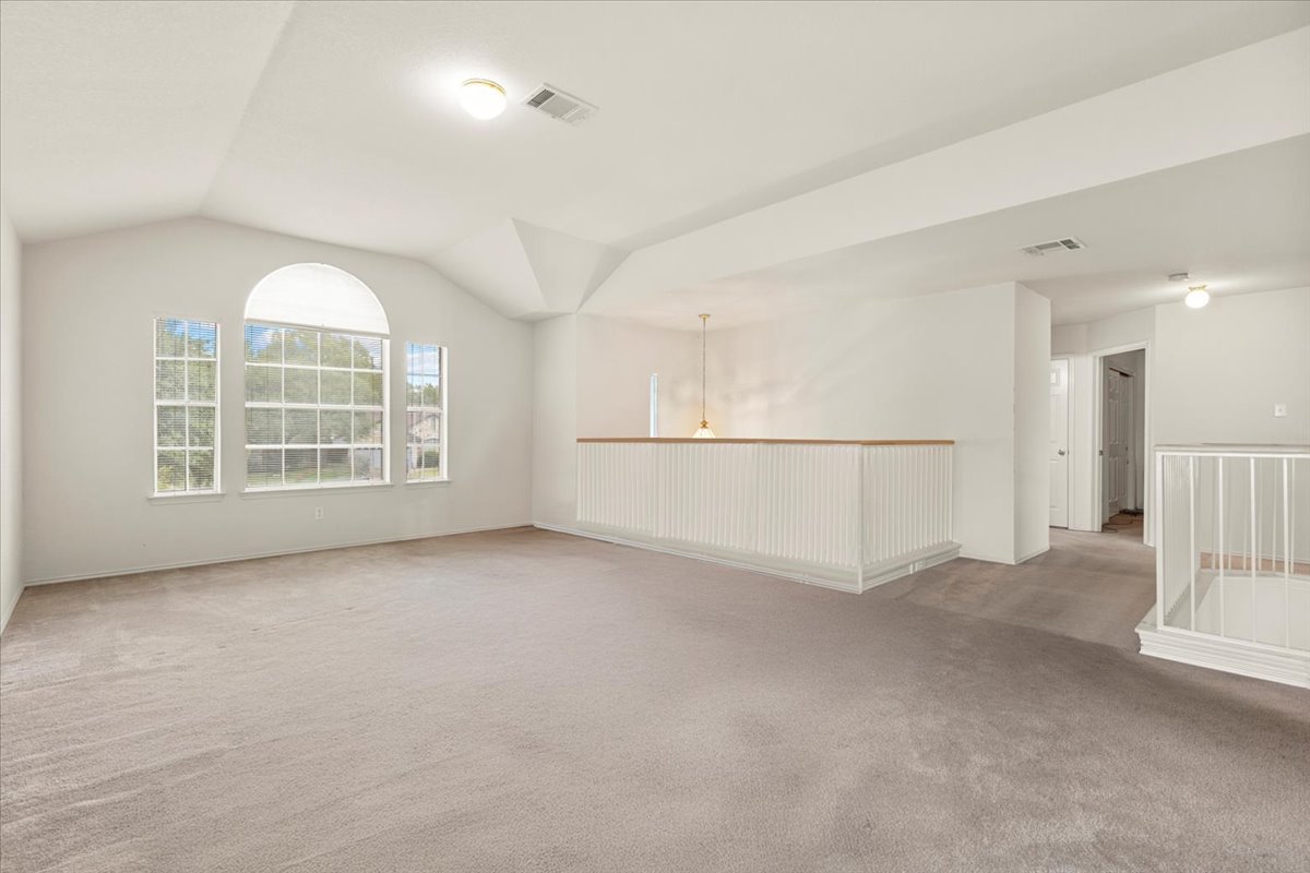 3929 Katzman Drive Austin, TX 78728 - Photo 23 of 29 Unfurnished living room with light colored carpet and vaulted ceiling