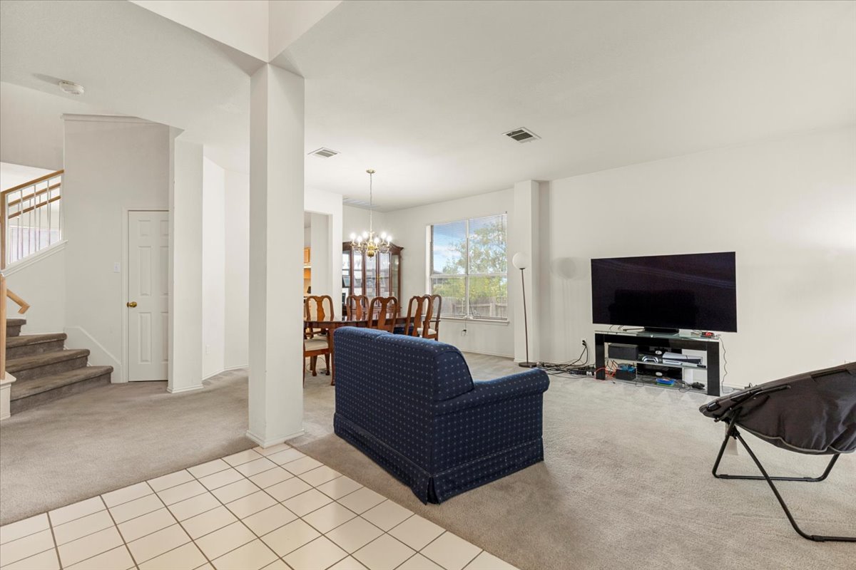 3929 Katzman Drive Austin, TX 78728 - Photo 6 of 29 Carpeted living area featuring stairway, tile patterned floors, and a chandelier