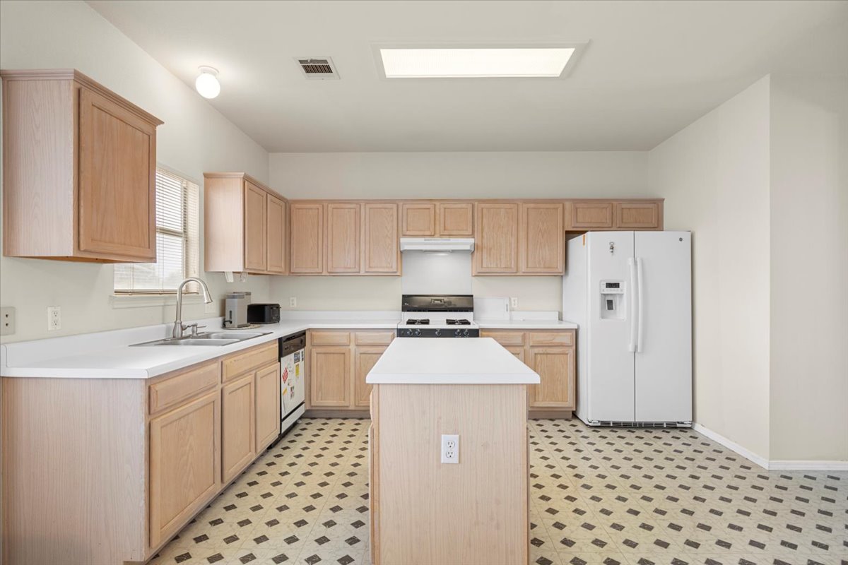 3929 Katzman Drive Austin, TX 78728 - Photo 8 of 29 Kitchen with light brown cabinets, white appliances, light countertops, a center island, and light floors