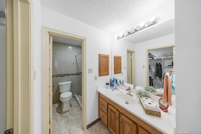a spacious bathroom with a double vanity sink a toilet and a mirror