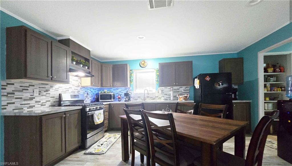 612 Hunting Clb Avenue Montura Ranches, FL 33440 - Photo 18 of 49 a kitchen with a table chairs and wooden cabinets
