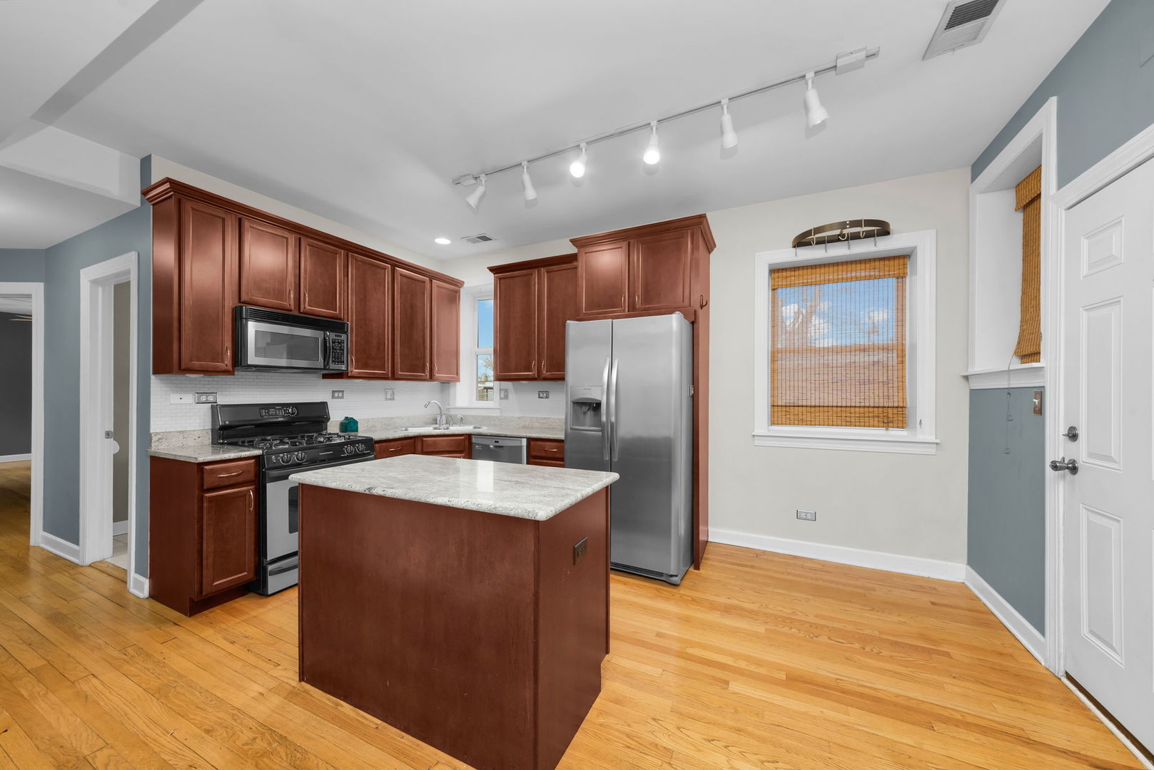 4241 North Kimball Avenue, Unit 2 Chicago, IL 60618 - Photo 3 of 16 a kitchen with stainless steel appliances granite countertop a refrigerator a sink dishwasher a stove with wooden cabinets and floor