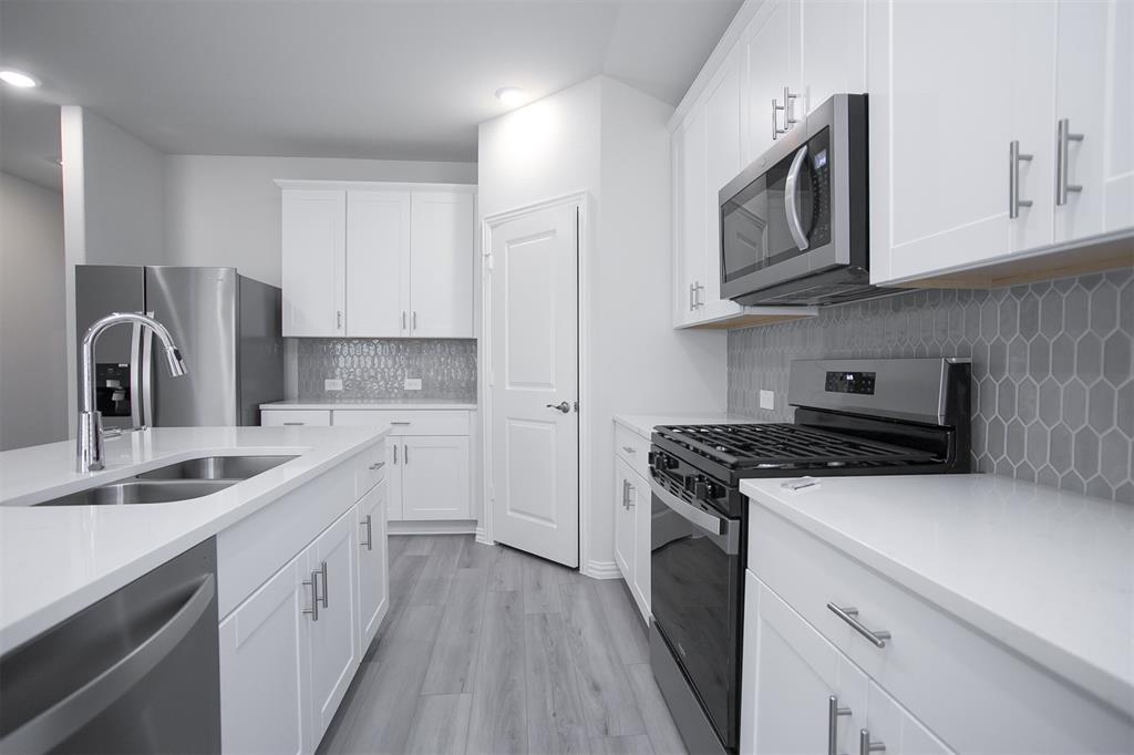 404 Castle Road Sherman, TX 75092 - Photo 5 of 25 a kitchen with cabinets appliances a sink and a counter top space